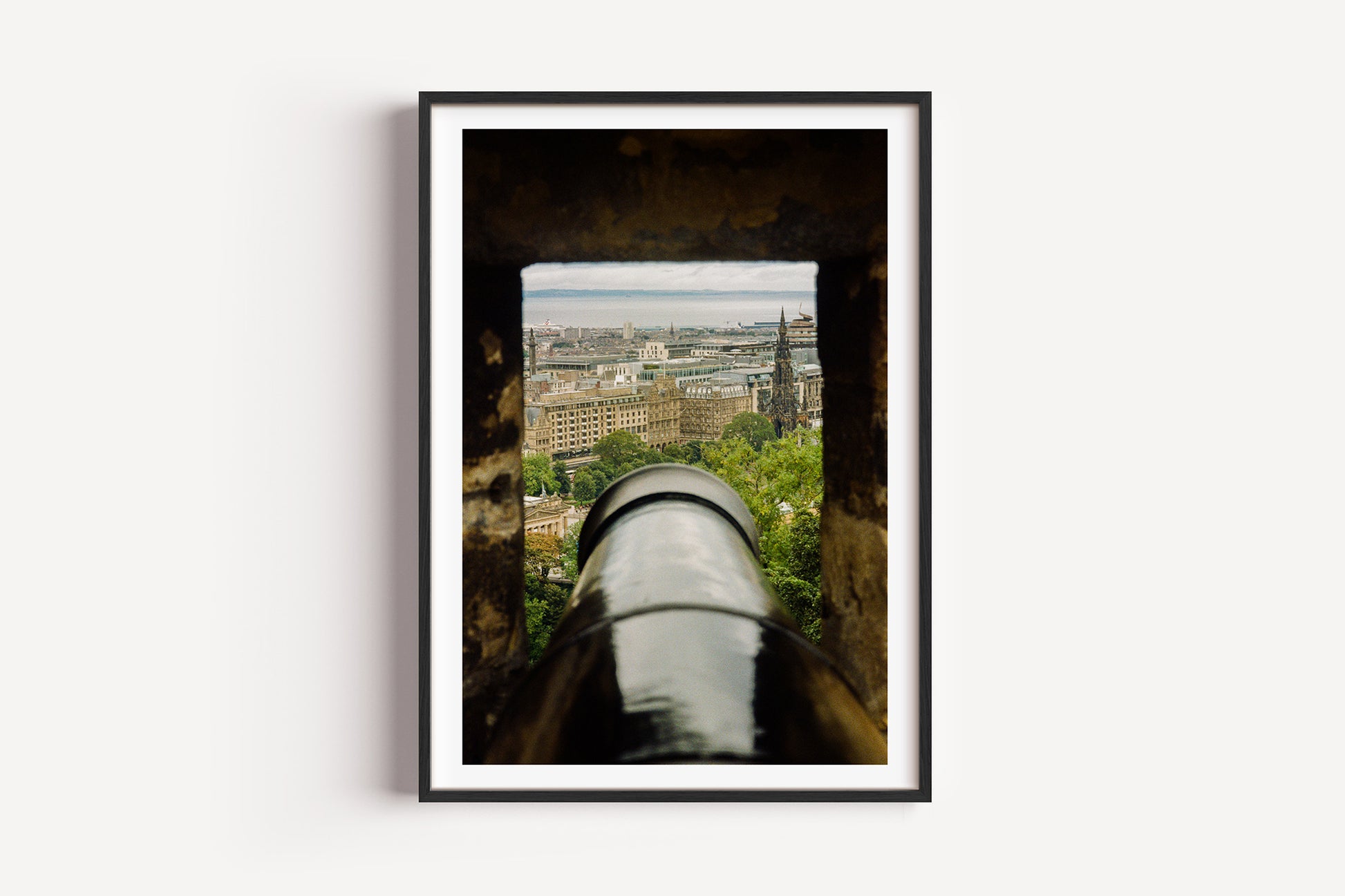 Framed artwork of a cityscape viewed through a cannon, on a white background