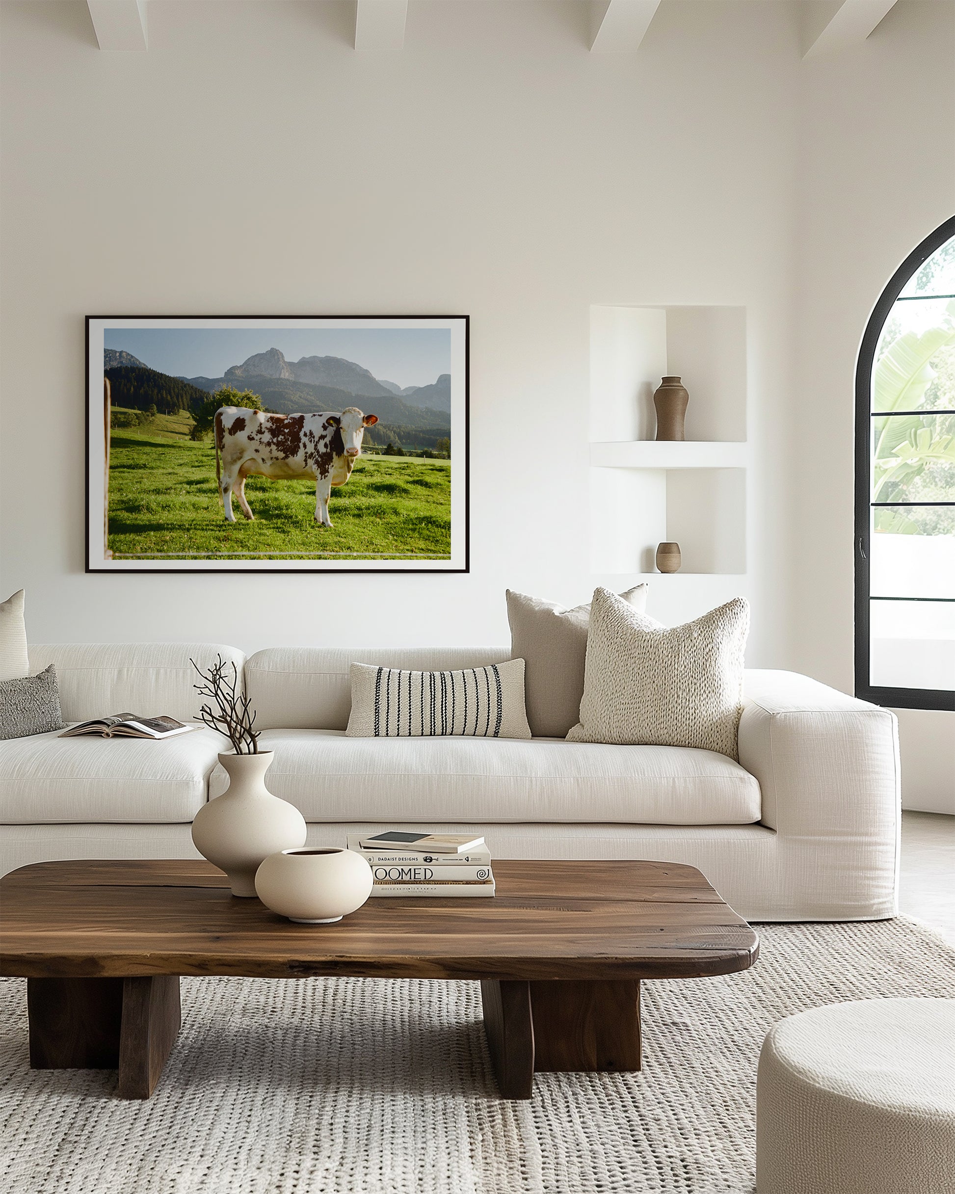 Modern living room with a white sofa, wooden coffee table, and a framed picture of a cow on the wall.