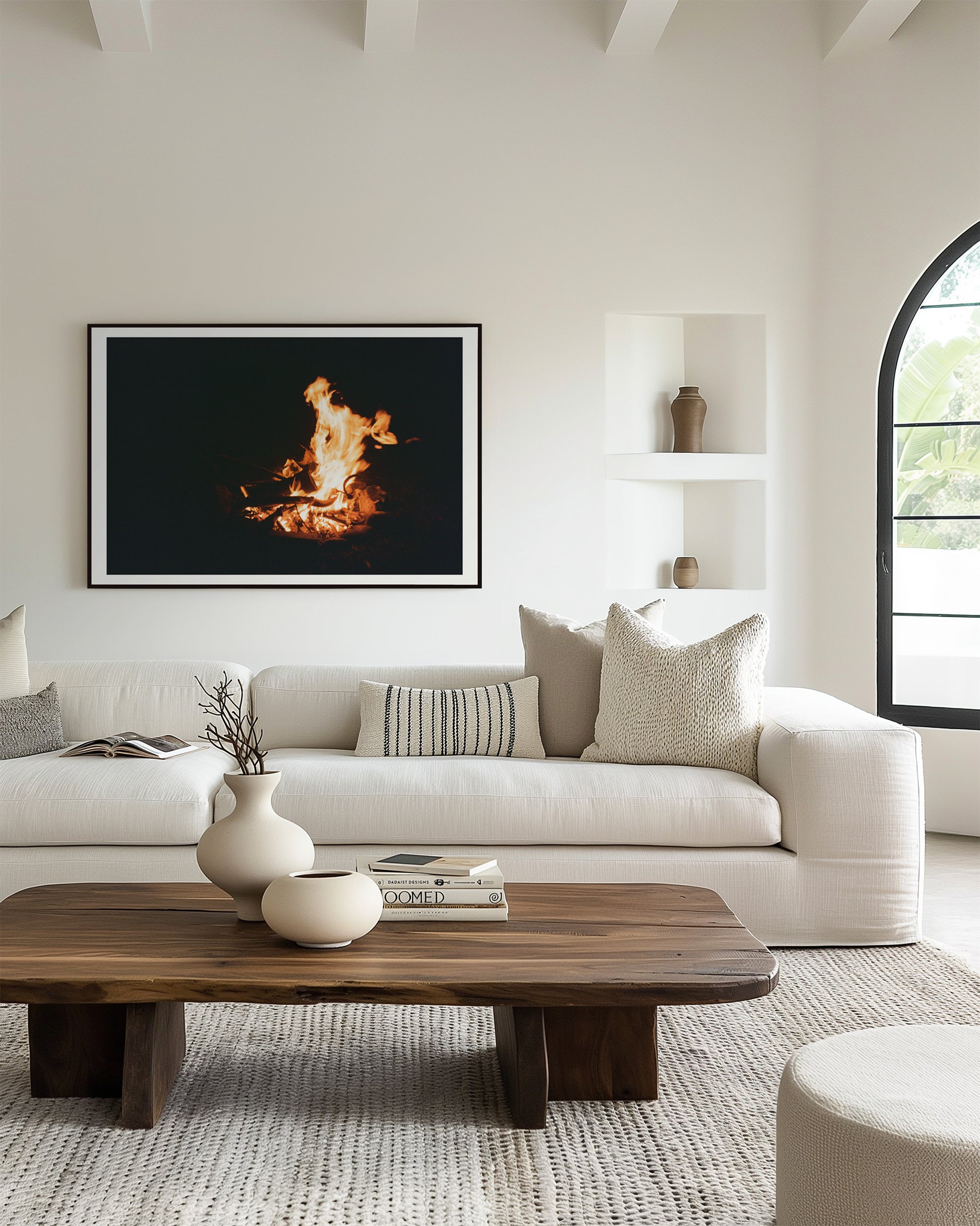 Modern living room with a white sofa, wooden coffee table, and a framed artwork of flames.