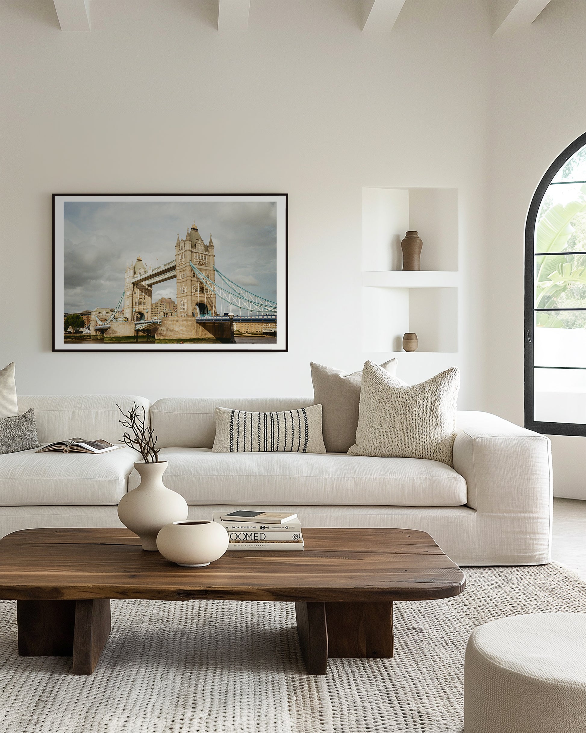 Modern living room with a white sofa, wooden coffee table, and a framed picture of a bridge.