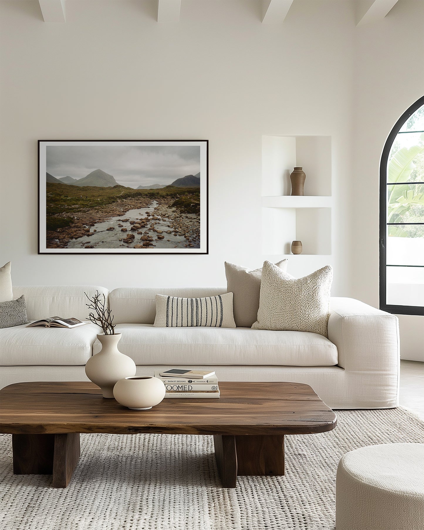 Modern living room with a white sofa, wooden coffee table, and framed landscape art.
