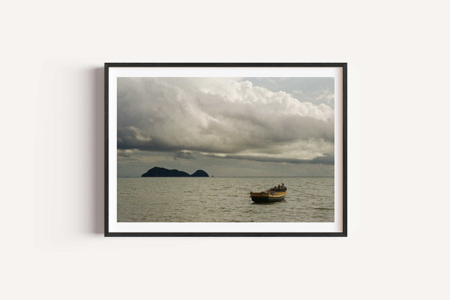 Framed photograph of a boat on water with a cloudy sky