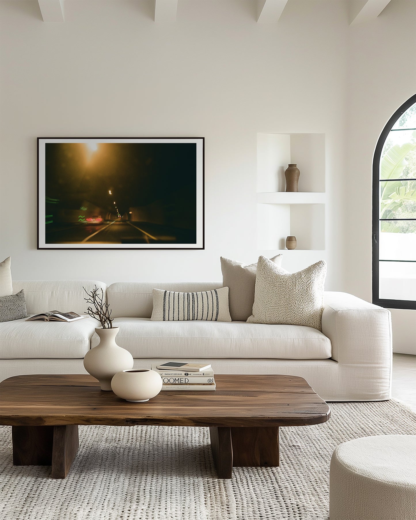 Modern living room with a white sofa, wooden coffee table, and framed artwork on the wall.