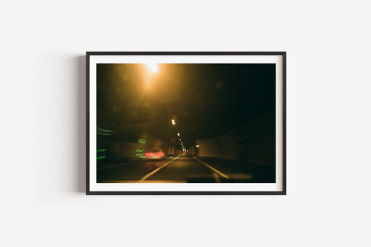Framed photograph of a dark road at night with lights.