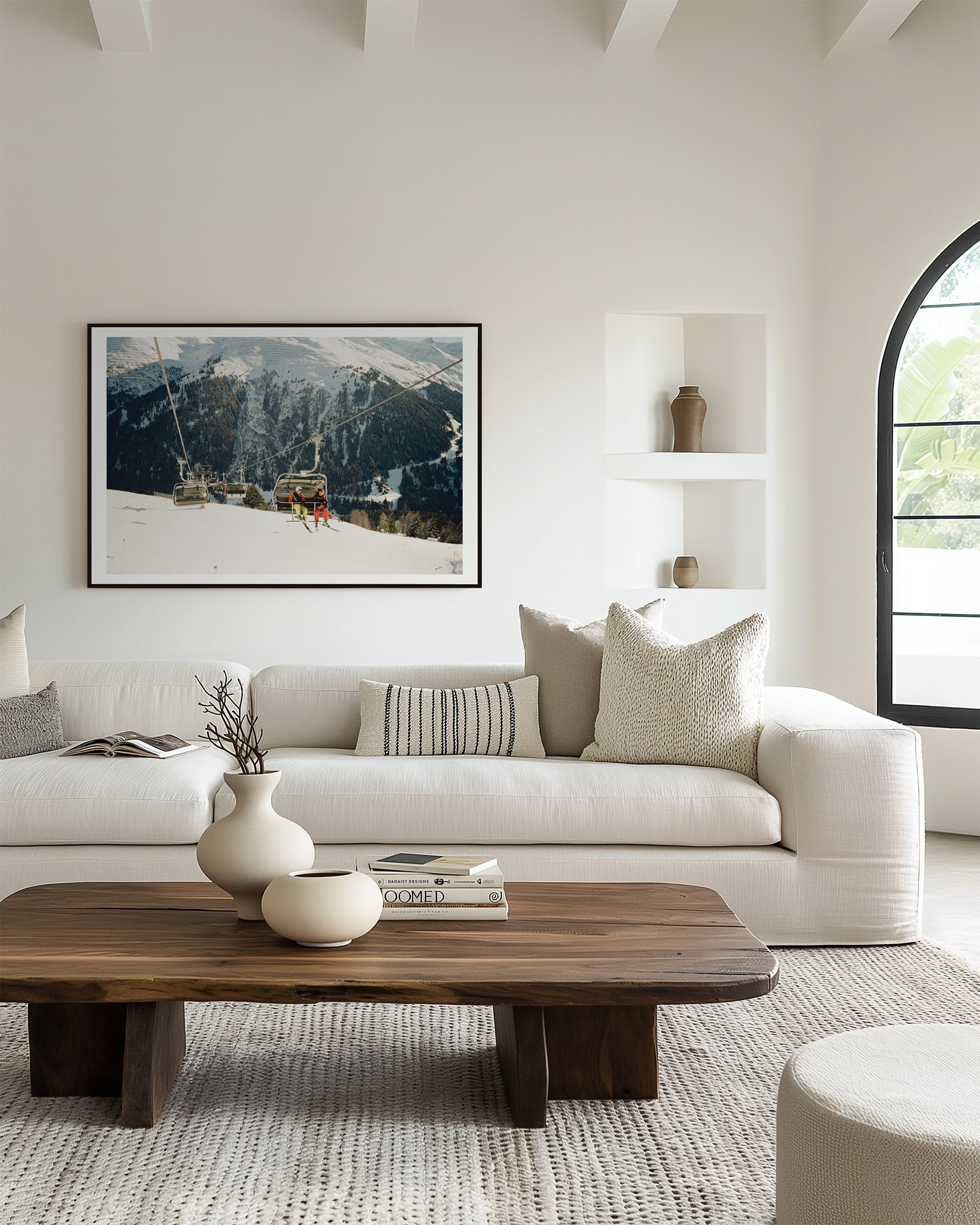 Modern living room with a white sofa, wooden coffee table, and mountain-themed artwork.